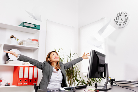 happy businesswoman in an office throwing papersの写真素材