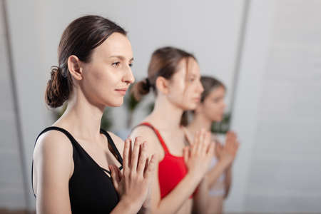 Three girls practicing yoga. Yoga instructor with her students meditating in a studio.の写真素材