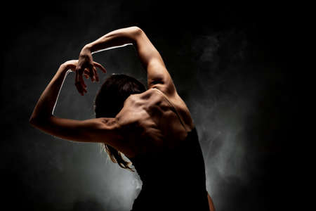half silhouette modern ballet dancer posing on dark background with smokeの写真素材