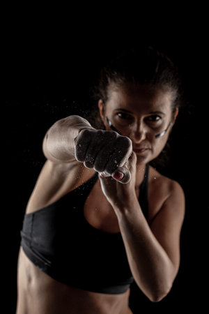 Kickboxer kirl with magnesium powder on her hands, punching with dust visible.の写真素材