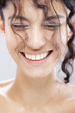 Beautiful brunette girl with long curly hair, studio portrait. Smiling happy face expression.の写真素材