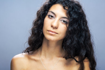 Beautiful brunette girl with long curly hair, studio portrait.