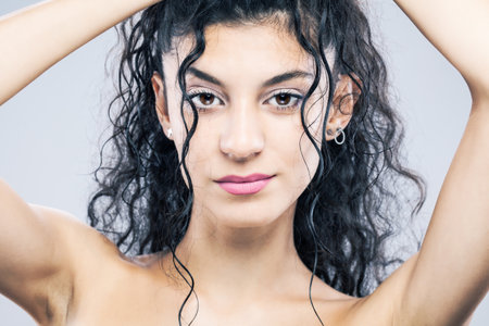 Beautiful brunette girl with long wet hair, studio portrait. Serious face expression.の写真素材