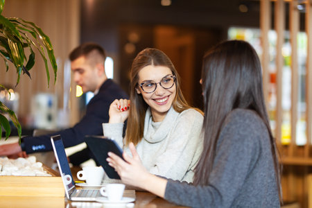 Two girls having a business meeting at a modern cafe. Happy smiling expressions,の写真素材