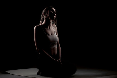 beautiful caucasian girl posing yoga in shadow, side litの写真素材