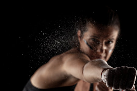 Kickboxer kirl with magnesium powder on her hands, punching with dust visible.の写真素材