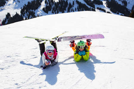 two female friends with ski and snowboard equipment posing on the snowの写真素材