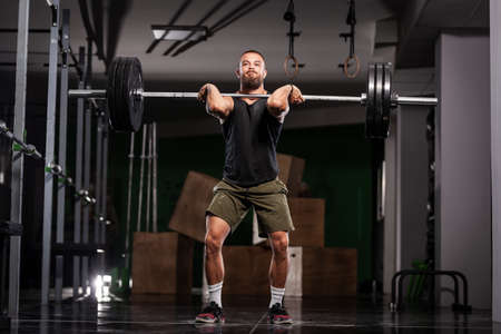 Muscular athlete lifting very heavy barbell.