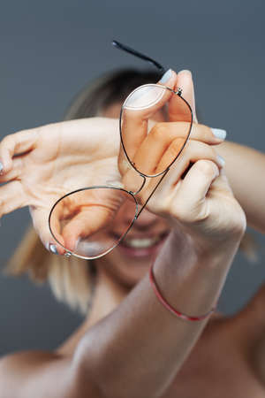 Beautiful girl fashion portrait. Holding glasses in hands.