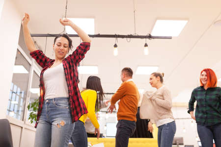 Team of successful multiethnic coworkers in modern office workplace dancing and celebrating success. Diversity happines concept.の写真素材