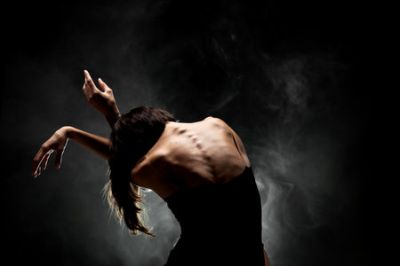 half silhouette modern ballet dancer posing on dark background with smokeの写真素材