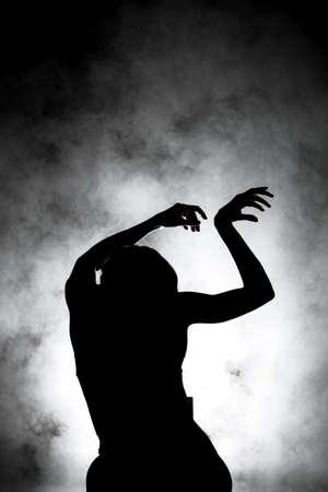 silhouette modern ballet dancer posing on dark background with smoke