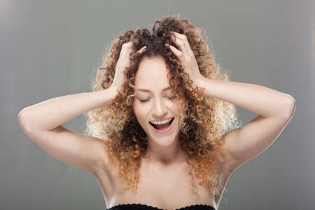 Beautiful brunette girl with long curly hair. Studio portrait. Happy smiling and singing face...