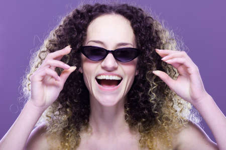 Beautiful girl with long curly hair fashion portrait wearing sunglassesの写真素材
