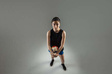 Handball player posing on light gray background. Girl posing with ball.