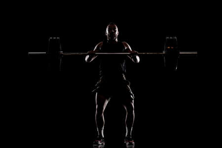 Athlete lifting barbell. Silhouette of a muscular man.