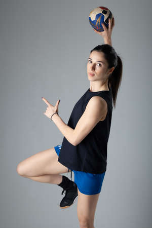 Handball player posing on light gray background. Girl jumping with ball.の写真素材