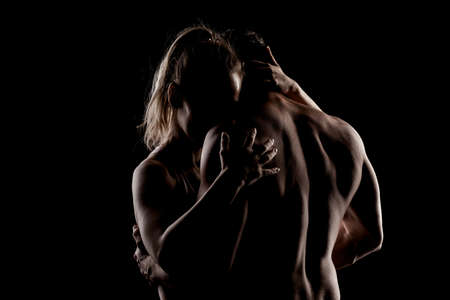 Fit couple posing together. Boy and girl side lit silhouettes on black background.の写真素材