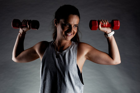 Fitness girl posing and lifting weights. Positive smiling expression.の写真素材