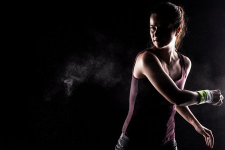 Kickboxer kirl with magnesium powder on her hands, punching with dust visible.の写真素材
