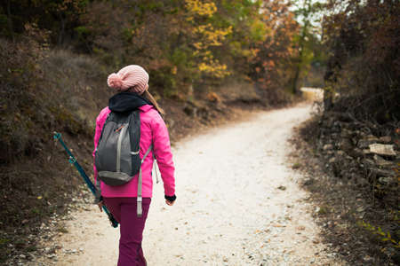 Hiker girl walking on a path in the mountains. Back view of backpacker with pink jacket in a forest. Healthy fitness lifestyle outdoors.の写真素材
