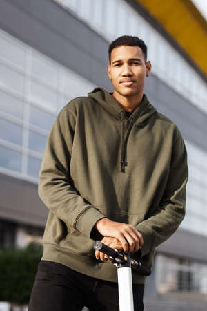 young african american man in casual clothing posing on electric scooter