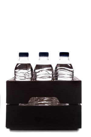 Group of small plastic water bottles in wooden crate. Studio photo silhouette.の写真素材