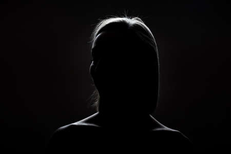 silhouette contour of a beautiful blond girl. Side lit studio portrait on dark background.の写真素材