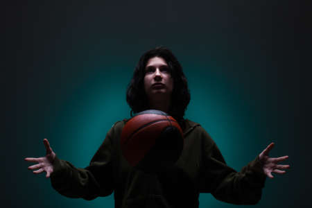 Teenage girl with basketball. Studio portrait with neon blue colored background.の写真素材