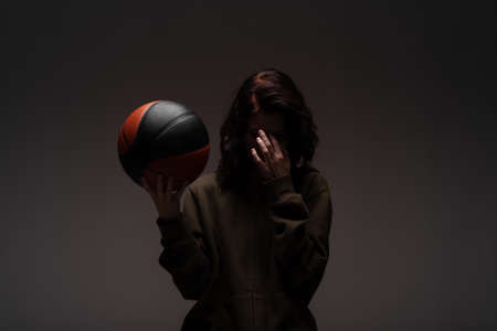 Teenage girl with basketball. Silhouette studio portrait on dark background.の写真素材