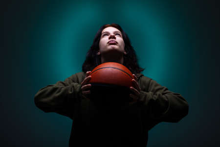 Teenage girl with basketball. Studio portrait with neon blue colored background.の写真素材