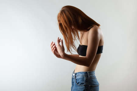 Beautiful girl with burnt orange hair stretching and making ballet pose. Studio portrait on gray background.の写真素材
