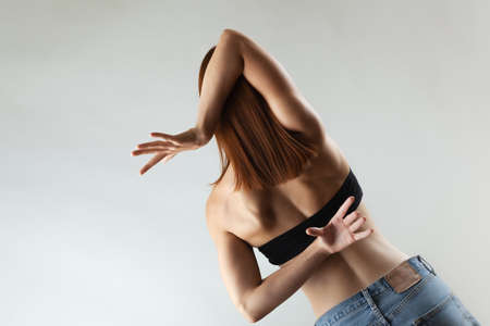 Beautiful girl with burnt orange hair stretching and making ballet pose. Studio portrait on gray background.の写真素材