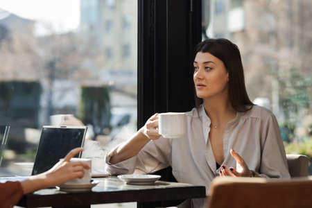 Two young business women in a cafe having one on one meeting. Friends after work talking gossiping...