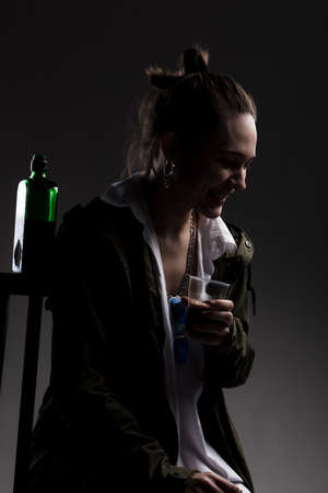 studio portrait of a beautiful girl with alcohol bottle and a plastic cup.の写真素材