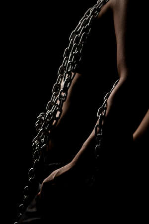 Strong fit girl with metal chain. Pulling and posing against black backgroundの写真素材