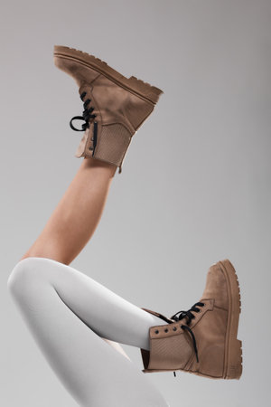 Sexy female legs wearing boots. One leg with white leggings.