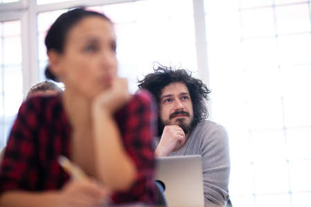 Students listening to a lecturer in a classroom. Smart young people study at a college.