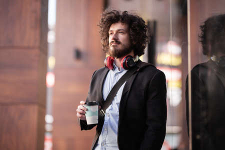 Man with clumsy hair and headphones posing near window with reflections. Hipster style businessman on a coffe break.の写真素材