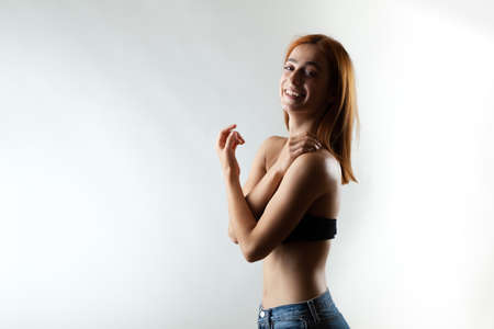 Beautiful girl with burnt orange hair posing and smiling in studio against gray background.の写真素材