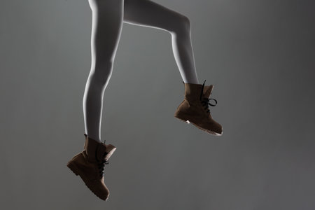 Sexy female legs with white leggings and waterproof boots. Side lit half silhouette.の写真素材