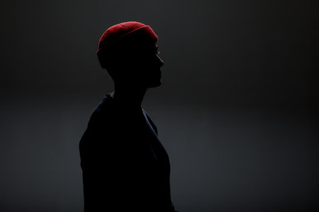 Girl with short hair wearing blouse and red hat against gray background.の写真素材