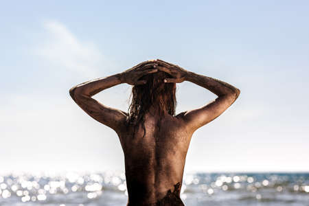 Sexy girl sitting on a beach. Body covered with sandの写真素材