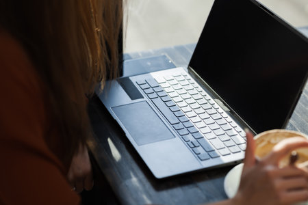 Young businesswoman in a cafe bar or restaurant. Freelancer girl working on laptop and having coffee at a window table.の写真素材