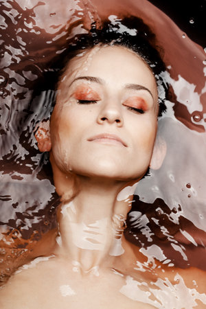 Underwater beauty portrait of a beautiful caucasian girl. Eyes closed. Red colored water.の写真素材