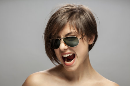 Beautiful girl fashion portrait wearing sunglasses. Surprised angry screaming face expression.の写真素材