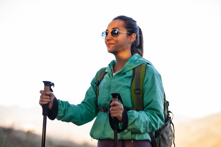 Backpacker hiker girl with hiking poles during sunset in the mountains.の写真素材