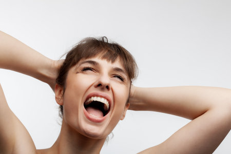 studio portrait of a screaming beautiful brunette girl with short hair looking up isolated on white background.の写真素材