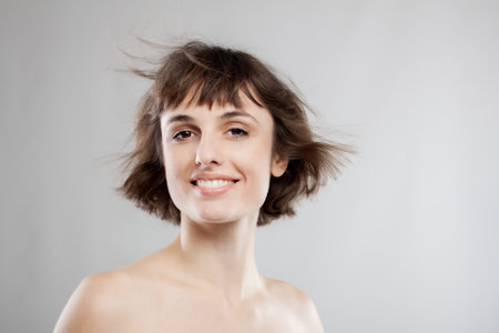 studio portrait of a beautiful brunette girl with short hair in the airの写真素材