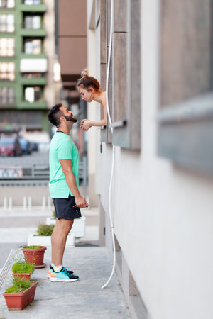 Couple in love. Boy standing outdoors talking with girl from within a window.の写真素材